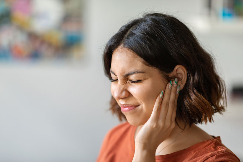 At home, a young woman is going through an episode of ear pain.