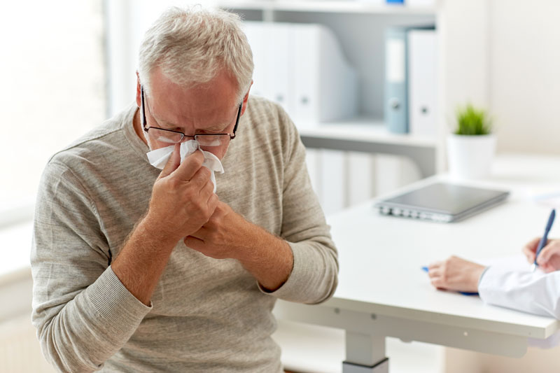 Man sneezing into a tissue