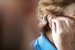Close-up of an older woman having a custom hearing aid inserted into her ear