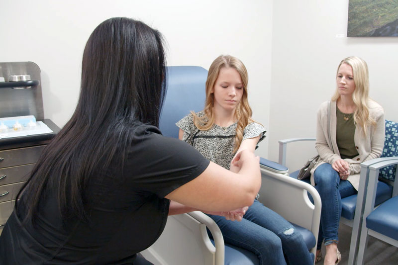 Medical team performing an allergy test on the forearm of a young female patient