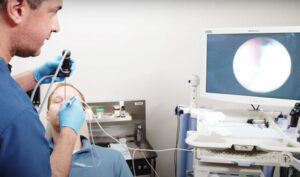 Male ENT Physician performs a balloon sinuplasty procedure in a medical office.