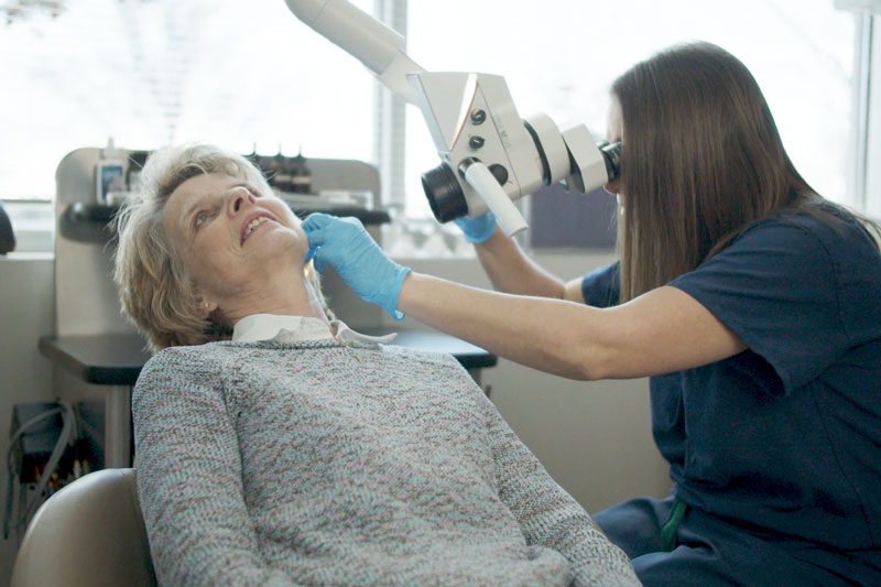 Female physician performs an examination of the ear on an older woman in a medical office.