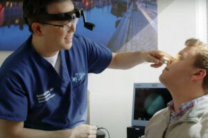 An ENT examines the nose of a male patient in a medical office.