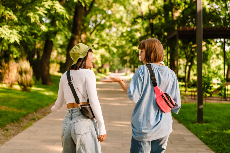 Two women walking outside and engaged in conversation.