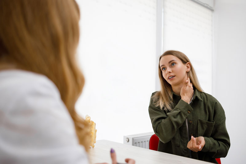 Young woman consulting with her doctor about a neck issue