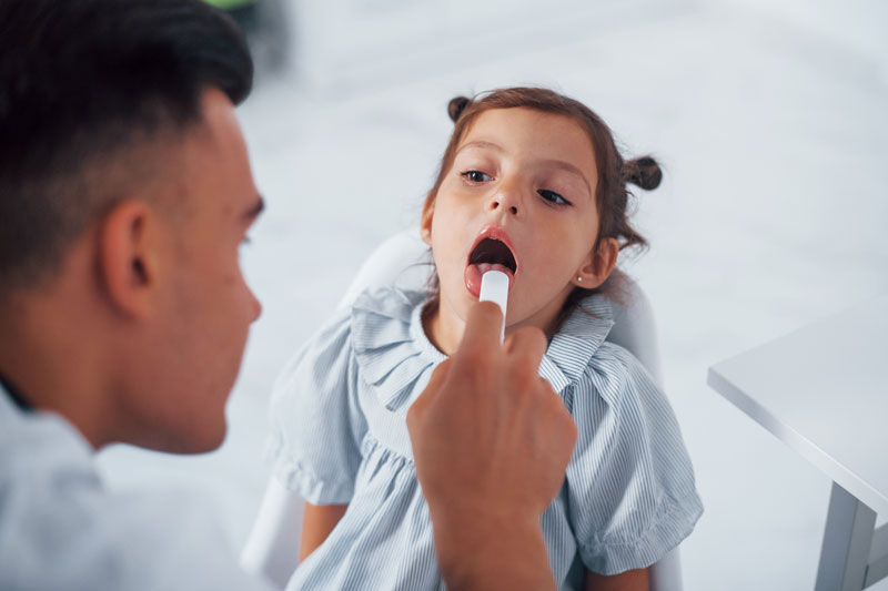 Male physician checking the throat of a young girl