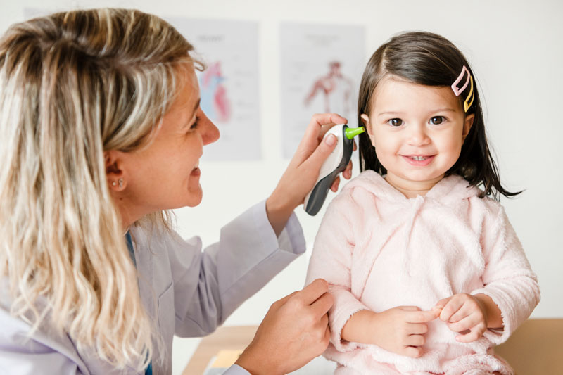 Young girl having her ear examined by female physician