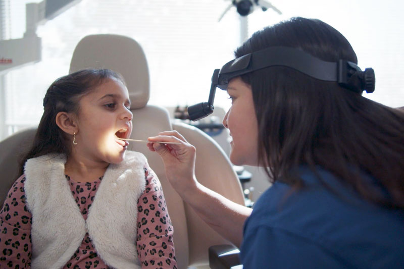 Female physician examining a young girl with her mouth open