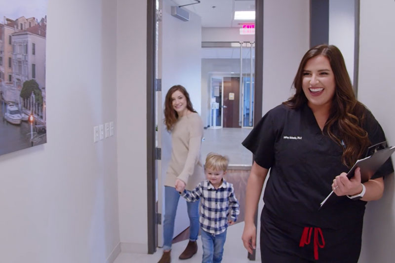 Female physician walking with a mother holding her son’s hand