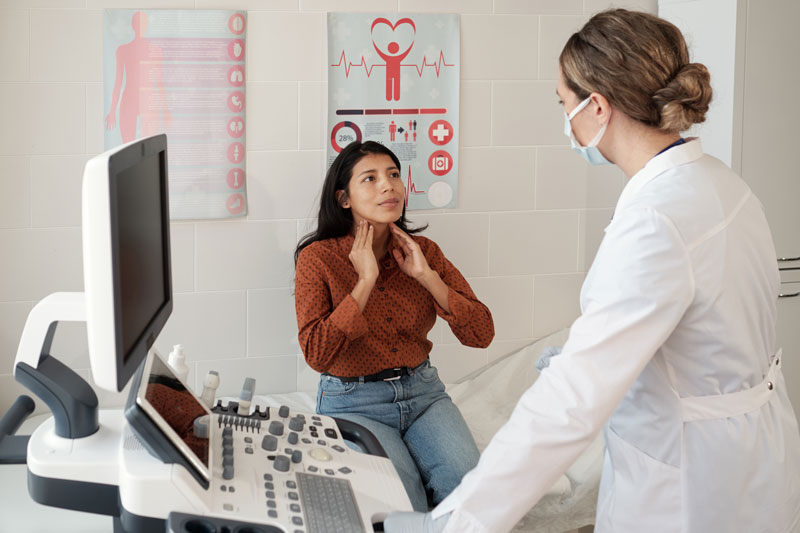 young hispanic female patient touching her thyroid