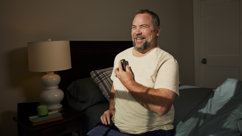 Man sitting in bed holding remote for the Inspire device