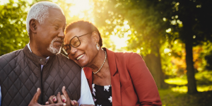 Older couple holding hands, smiling, and enjoying the outdoors and their ENT health wellness