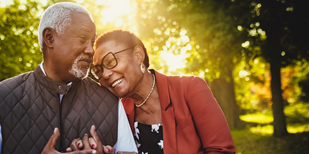 Older couple holding hands, smiling, and enjoying the outdoors and their ENT health wellness